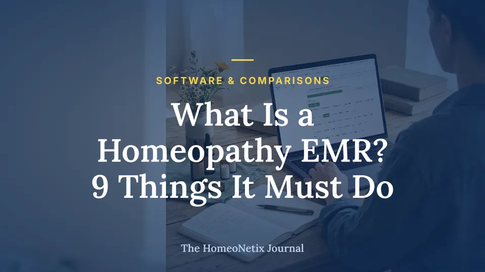 A person works on a laptop at a wooden desk with homeopathy remedies, a notebook, and flowers.